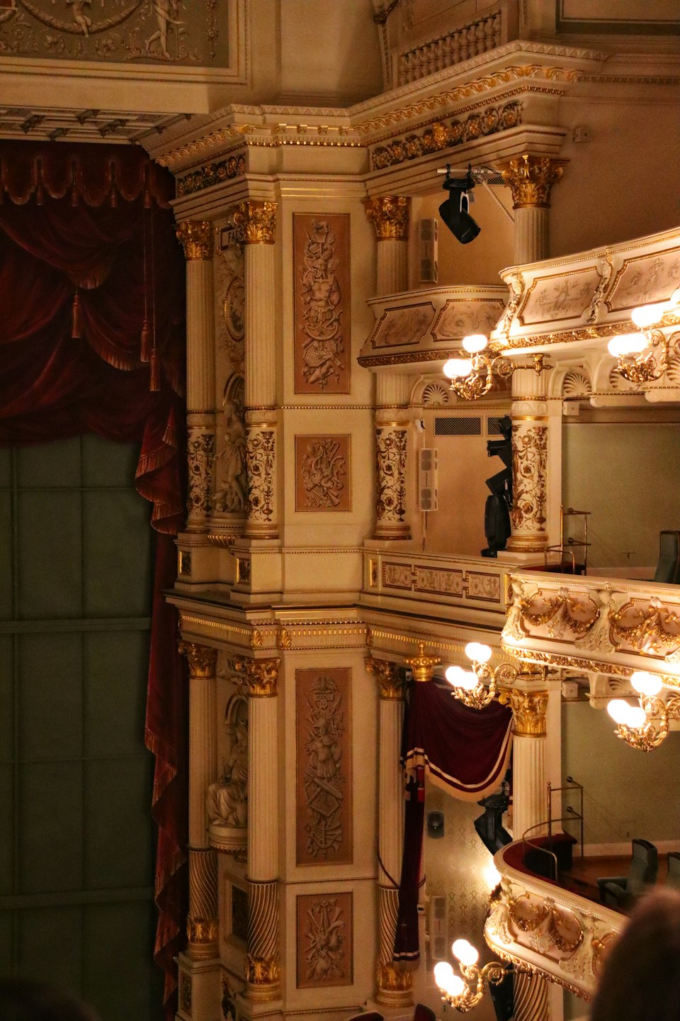Balconi dorati e sontuosi con tende di velluto all'interno di uno storico teatro.